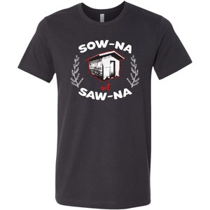 May include: A dark gray t-shirt with a white graphic design. The graphic features a small house with the text "Sow-Na not Saw-Na" in white with the word "not" in red.
