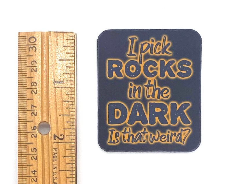 May include: A dark blue square sticker with orange text that reads "I pick ROCKS in the DARK Is that weird?"