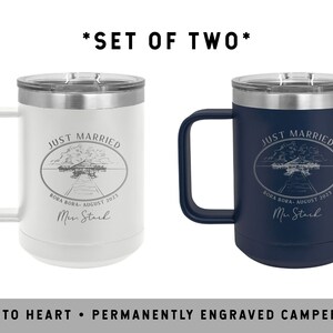 May include: Set of two engraved stainless steel camper mugs. The mugs are white and navy blue with the text "Just Married" and a wedding date. The text is engraved in a silver color.