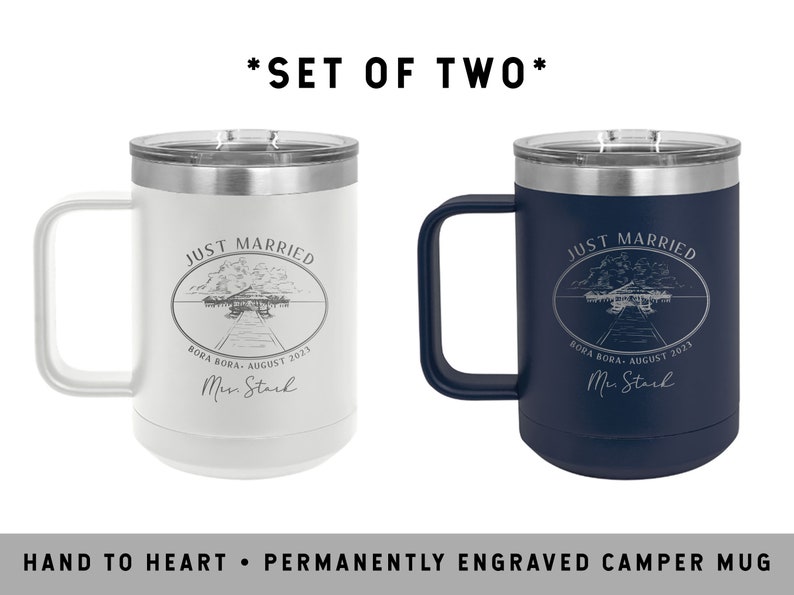 May include: Set of two engraved stainless steel camper mugs. The mugs are white and navy blue with the text "Just Married" and a wedding date. The text is engraved in a silver color.