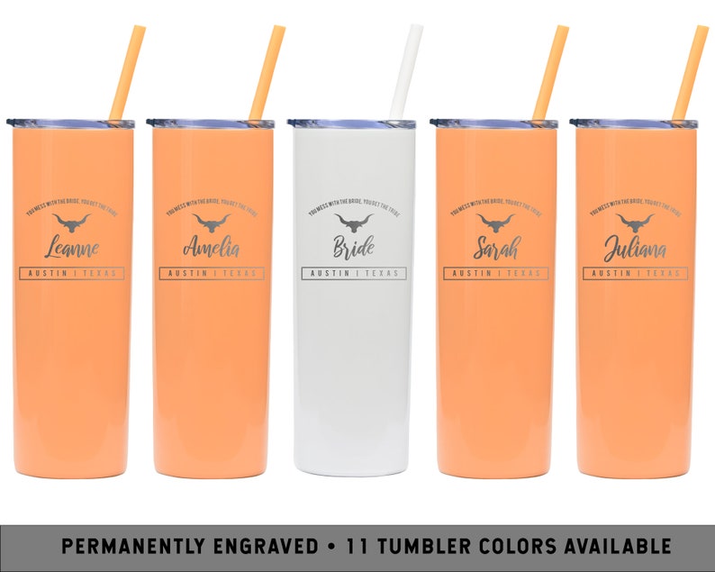 May include: Five stainless steel tumblers with orange and white finishes. Each tumbler has a straw and features a black and white graphic of a longhorn steer with the text "You mess with the bride, you mess with the crew" and a personalized name. The names are Leanne, Amelia, Bride, Sarah, and Juliana. The text "Austin, Texas" is also included on each tumbler.