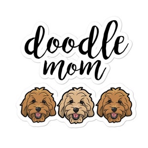 May include: Doodle Mom text with three cartoon doodle dogs in a row. The dogs are brown and white with black noses and eyes.