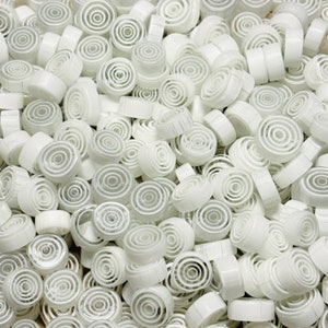 May include: A pile of white ceramic tiles with concentric circles in a variety of sizes. The tiles are smooth and glossy.