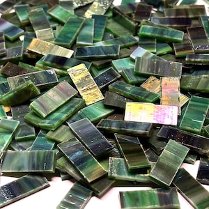 Puede incluir: Un montón de baldosas rectangulares de vidrio en tonos verdes, turquesas y dorados. Las baldosas varían en color y opacidad, creando una apariencia texturizada y en capas. Estas baldosas de mosaico son adecuadas para varios proyectos de artesanía.