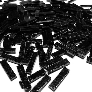 Może przedstawiać: Duża sterta czarnych szklanych płytek mozaikowych. Płytki są prostokątne i mają błyszczące wykończenie.