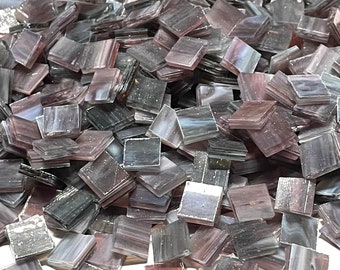 May include: A pile of small, square, iridescent glass tiles in shades of gray and purple. The tiles are perfect for crafting and mosaic projects.