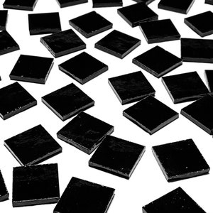 Puede incluir: Una gran cantidad de azulejos cuadrados negros, esparcidos sobre una superficie blanca. Los azulejos son brillantes y reflejan la luz.