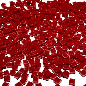 May include: A large quantity of small, red, square tiles. The tiles are scattered on a white surface.