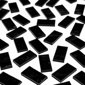 May include: A collection of black rectangular tiles scattered on a white surface. The tiles are smooth and glossy.