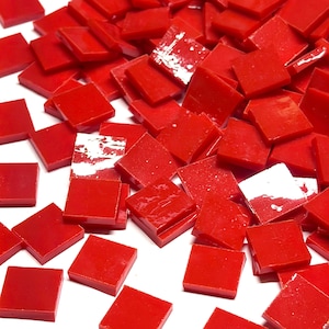 May include: A collection of small, square, vibrant red glass tiles scattered across a surface. Each tile features a smooth, glossy finish with sharp, clean edges, creating a uniform appearance. The tiles are opaque and consistent in color.