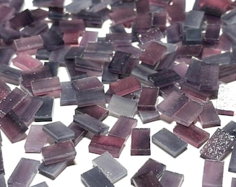 Puede incluir: Una gran cantidad de pequeñas baldosas de mosaico de vidrio rectangulares en tonos de morado, gris y blanco. Las baldosas tienen un acabado ligeramente iridiscente.
