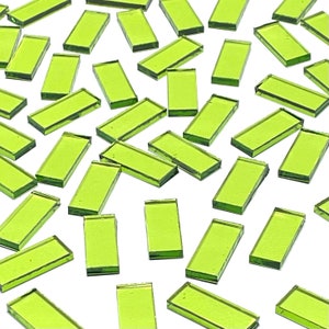 May include: A large quantity of small, rectangular, lime green glass tiles. The tiles are scattered on a white surface.