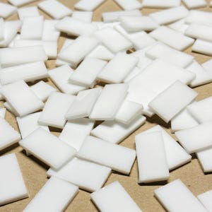 May include: A large pile of small, white, rectangular adhesive squares.