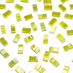 Puede incluir: Una colección de pequeñas baldosas de vidrio amarillo iridiscente. Las baldosas son de forma rectangular y tienen una superficie ligeramente texturizada.