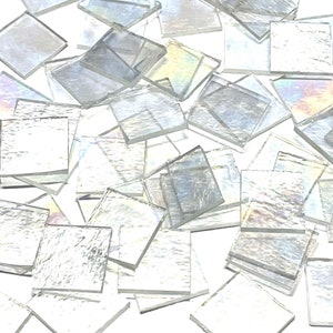 May include: A pile of iridescent white glass mosaic tiles. The tiles are square and have a slightly textured surface.