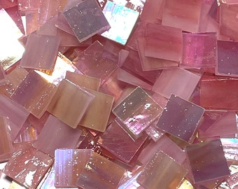 Puede incluir: Un montón de azulejos de mosaico de vidrio rosa iridiscente. Los azulejos son cuadrados y tienen una superficie ligeramente texturizada.