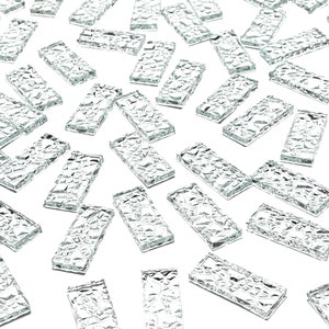 May include: A collection of clear glass tiles with a textured surface. The tiles are rectangular and have a slightly irregular shape.