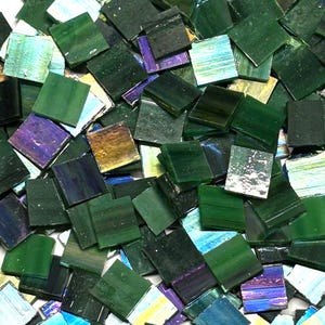 May include: A collection of small, square glass mosaic tiles in various shades of green, with hints of blue, purple, and gold. The tiles have a glossy finish and are scattered, creating a textured and colorful surface. Ideal for craft projects.