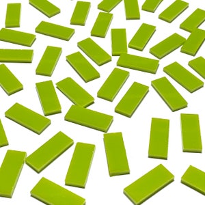 May include: A large quantity of small, rectangular, lime green tiles. The tiles are scattered on a white surface.