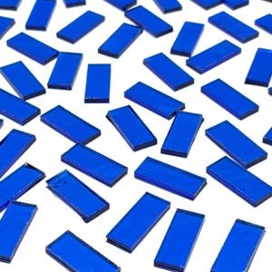 May include: A collection of small, rectangular, blue glass tiles. The tiles are scattered on a white background.