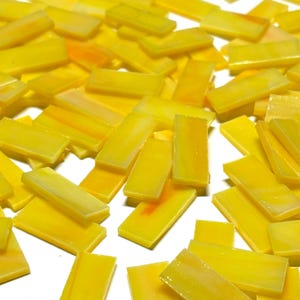 Puede incluir: Una colección de azulejos de vidrio amarillo en forma rectangular. Los azulejos tienen un ligero brillo iridiscente.