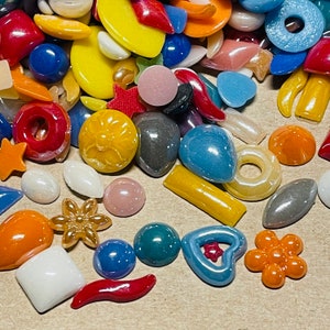 May include: Assortment of colorful glass and ceramic tiles in various shapes, including stars, hearts, circles, and flowers. The tiles are perfect for crafting projects, mosaics, and home decor.