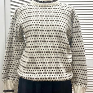 May include: A white and brown patterned jumper with long sleeves and a crew neck. The jumper has a brown trim around the neck and cuffs.