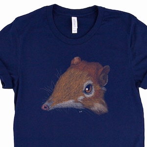 Pode incluir: Uma camiseta azul marinho com uma ilustração marrom e branca de um pequeno mamífero com um focinho longo. O mamífero está olhando para a esquerda da imagem.