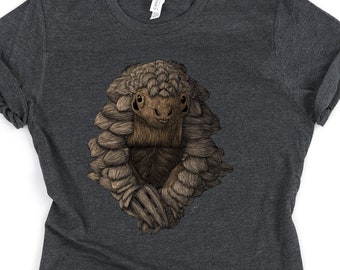 May include: A dark heather grey t-shirt with a graphic of a pangolin peeking out from its shell. The pangolin is brown and has a cute expression.