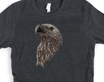 May include: A dark heather grey t-shirt with a detailed illustration of a brown and white eagle's head.