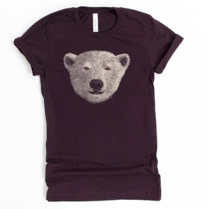 May include: A dark purple t-shirt featuring a white polar bear face graphic.