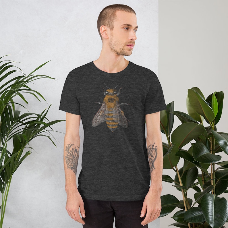 Może przedstawiać: Szary t-shirt w ciemnym odcieniu melanżu z szczeg&oacute;łową ilustracją pszczoły w odcieniach brązu i ż&oacute;łci.