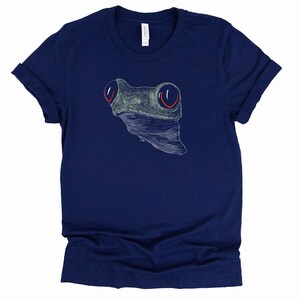 May include: A navy blue t-shirt with a white line drawing of a frog's head with red eyes.