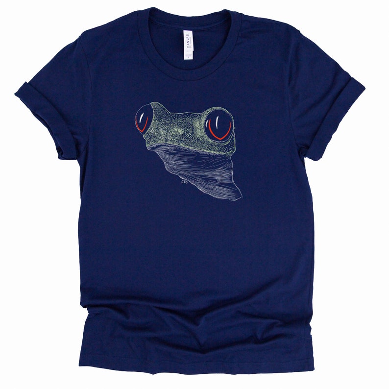 May include: A navy blue t-shirt with a white line drawing of a frog's head with red eyes.