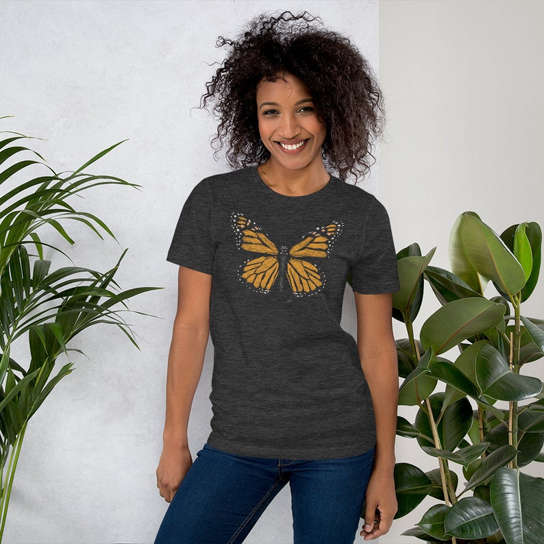 May include: A dark heather grey t-shirt with a graphic of a monarch butterfly in shades of orange and yellow.