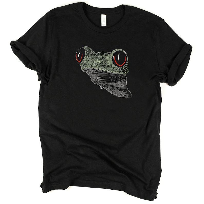 May include: Black t-shirt with a green and white line drawing of a frog's face with red eyes.