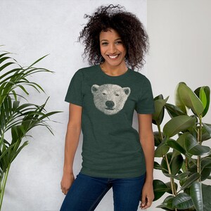 May include: A woman wearing a dark green t-shirt with a white polar bear face graphic. The t-shirt has short sleeves and a crew neck.