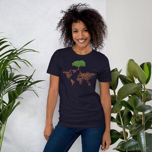 Puede incluir: Una camiseta azul marino con un gr&aacute;fico de un &aacute;rbol cuyas ra&iacute;ces forman la forma del mundo. El &aacute;rbol tiene hojas verdes y ra&iacute;ces marrones.