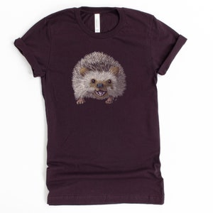 Peut inclure: Un t-shirt violet fonc&eacute; avec un imprim&eacute; d'un h&eacute;risson souriant.