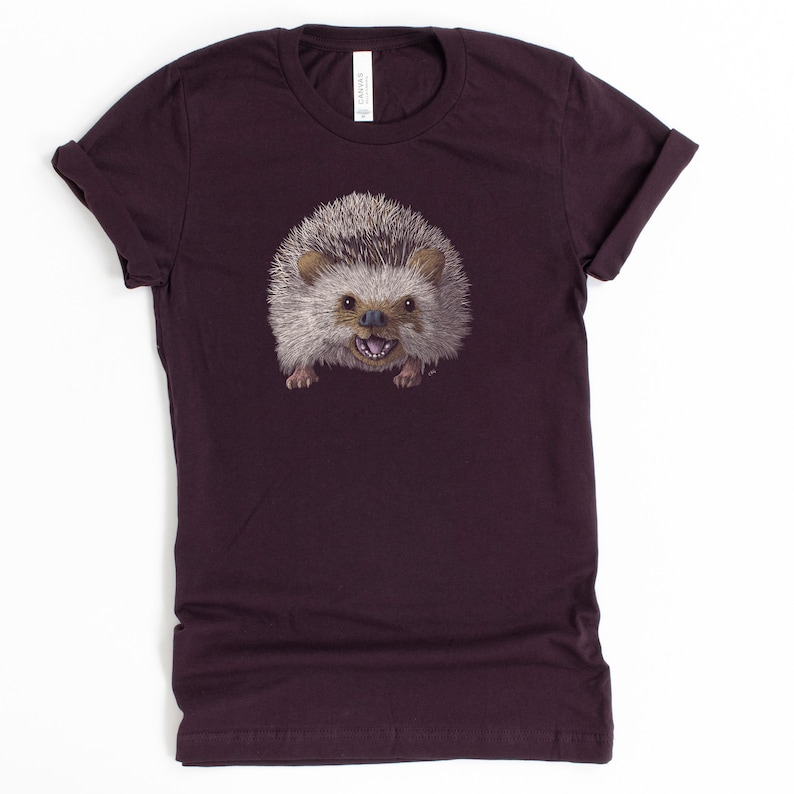 Peut inclure: Un t-shirt violet fonc&eacute; avec un imprim&eacute; d'un h&eacute;risson souriant.