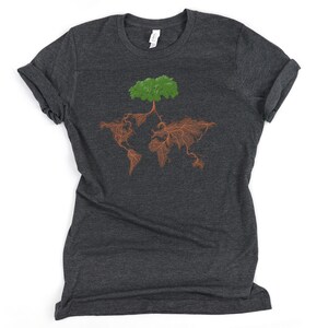 Puede incluir: Una camiseta gris oscuro con un &aacute;rbol verde cuyas ra&iacute;ces marrones forman la forma del mundo.