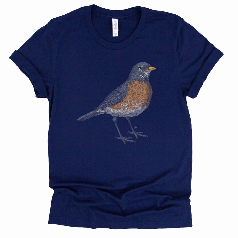 May include: A navy blue t-shirt with a detailed illustration of a robin bird in shades of gray, brown, and yellow.