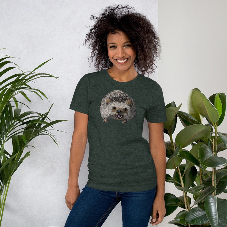 Peut inclure: Un t-shirt vert fonc&eacute; avec un motif d'un h&eacute;risson avec un sourire narquois. Le h&eacute;risson est brun et gris avec un ventre blanc.
