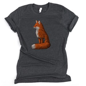 May include: A dark heather grey t-shirt featuring a graphic of a red fox sitting with its tail curled around its body.