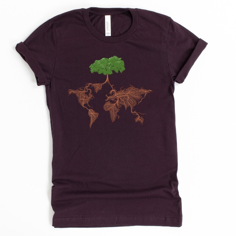 Puede incluir: Una camiseta de color morado oscuro con un &aacute;rbol verde que crece fuera del mundo, con ra&iacute;ces marrones.