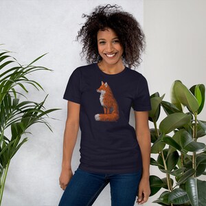 May include: A navy blue t-shirt featuring a graphic of a red fox sitting with its tail curled around its body.