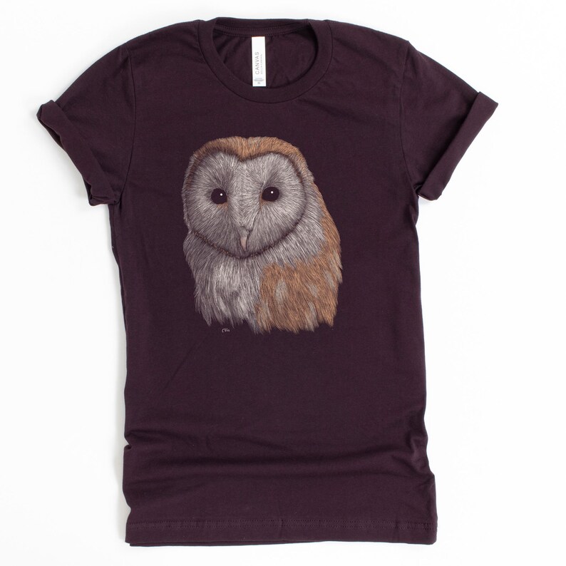 K&ouml;nnte beinhalten: Ein dunkelviolettes T-Shirt mit einer Illustration einer wei&szlig;en und braunen Scheune Eule auf der Vorderseite.