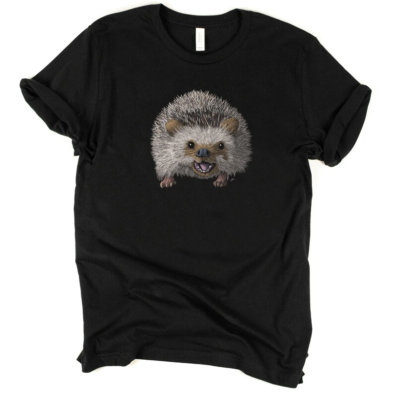 Peut inclure: Un t-shirt noir avec un imprim&eacute; d'un h&eacute;risson souriant. Le h&eacute;risson est brun et gris avec un ventre blanc et des yeux noirs.