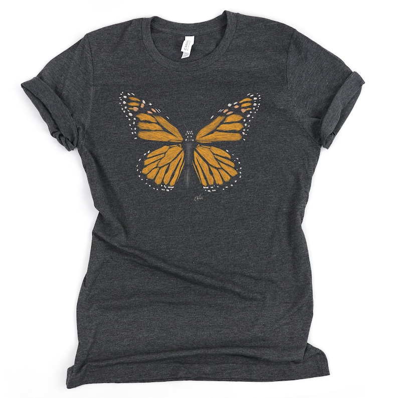 May include: A dark grey t-shirt with a graphic of a monarch butterfly in shades of orange and black.