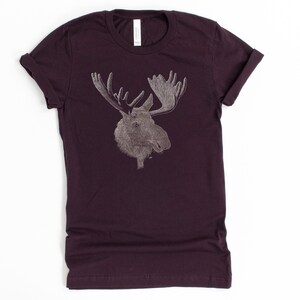 May include: A dark purple t-shirt with a white outline of a moose head with antlers.